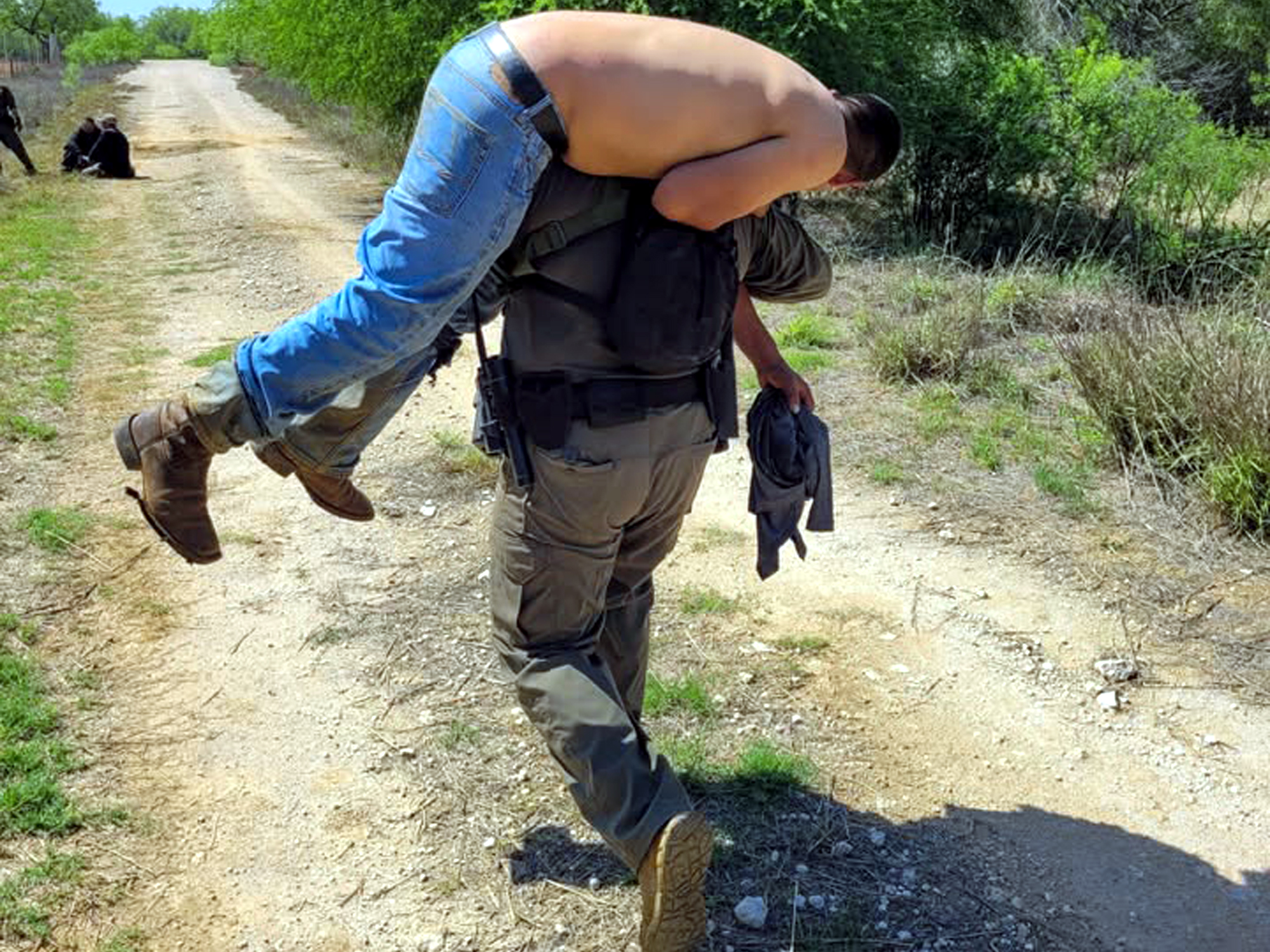 Agente fronterizo de Encinal carga a migrante deshidratado en zona rural