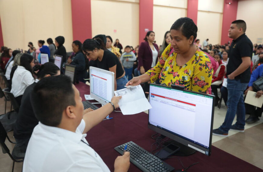 Madre de familia entrega identificación oficial para recibir beca escolar en módulo del Centro Cívico.