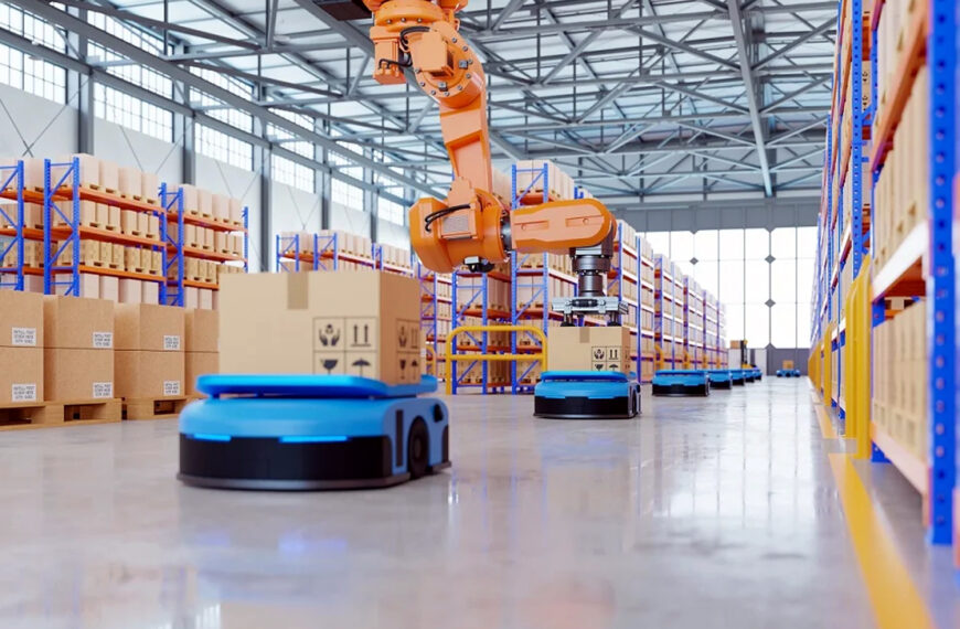 Interior de almacén automatizado donde un brazo robótico coloca cajas sobre vehículos móviles autónomos: ejemplo del entorno real que inspirará las becas bilingües de programación en robótica de almacenes.