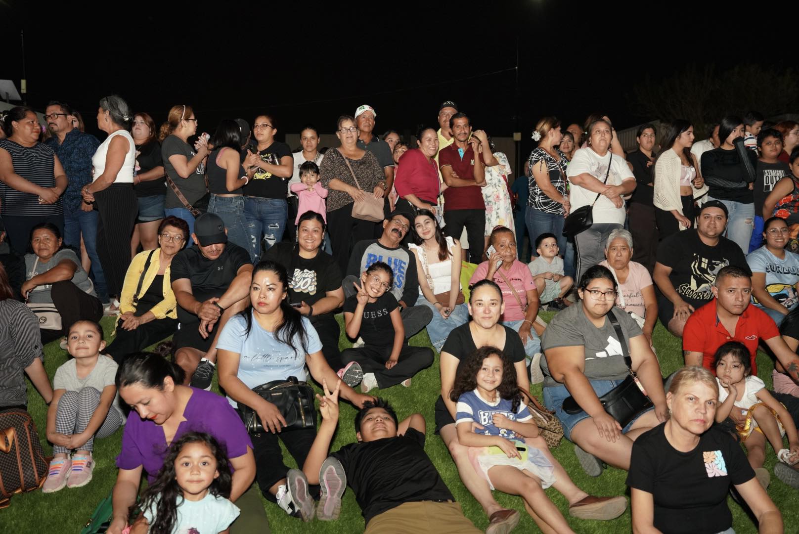 Familias sentadas en el rea de pasto de la Plaza de la Mujer durante el evento de inauguracin