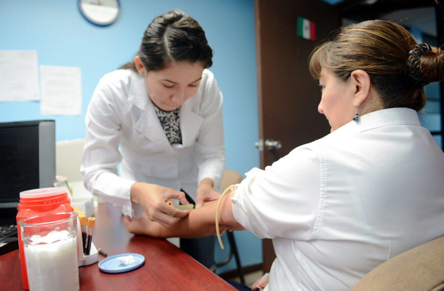 Una trabajadora de la salud realiza una toma de muestra sanguínea a una paciente adulta en un consultorio médico.