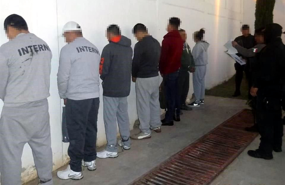 Internos del penal de Nuevo Laredo formados contra una pared durante un cateo en 2020, supervisados por personal de seguridad.