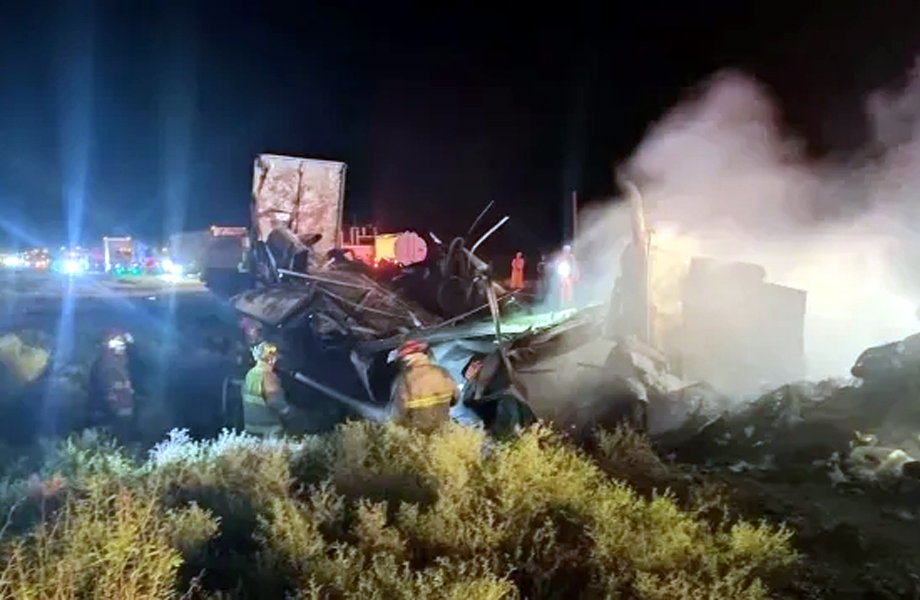 Restos de triler siniestrado mientras bomberos trabajan entre escombros y humo en la carretera MonterreyNuevo Laredo