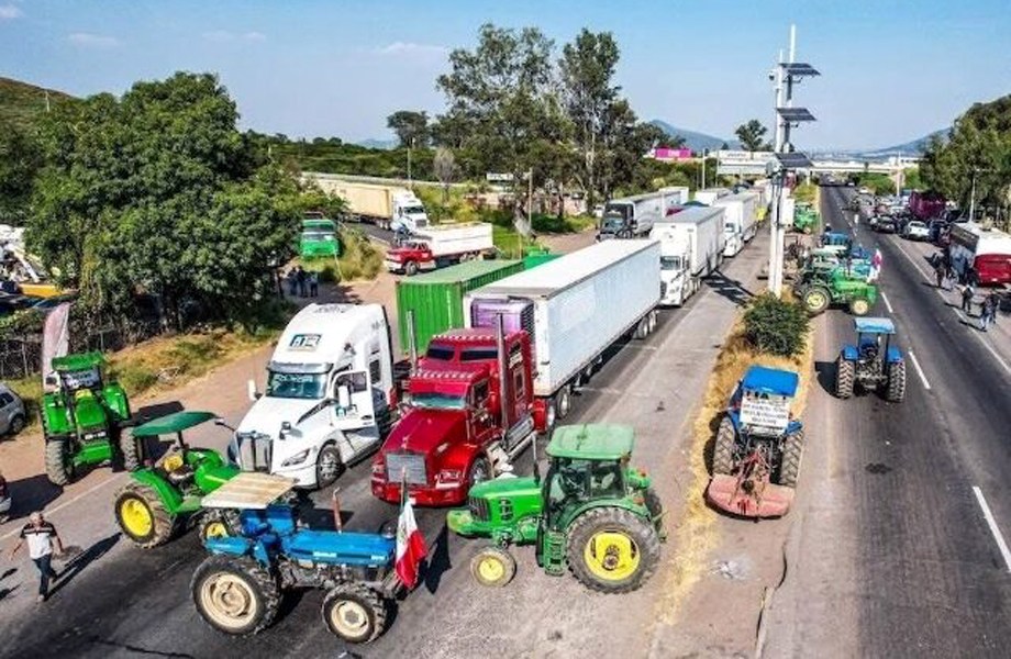 Tractores y tráileres bloqueando una carretera durante protestas de campesinos y transportistas.