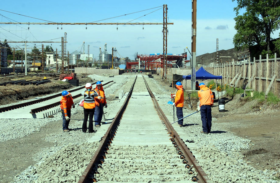 Cuadrilla de obreros con casco y chaleco naranja trabajando en la colocacin de nuevos rieles de tren
