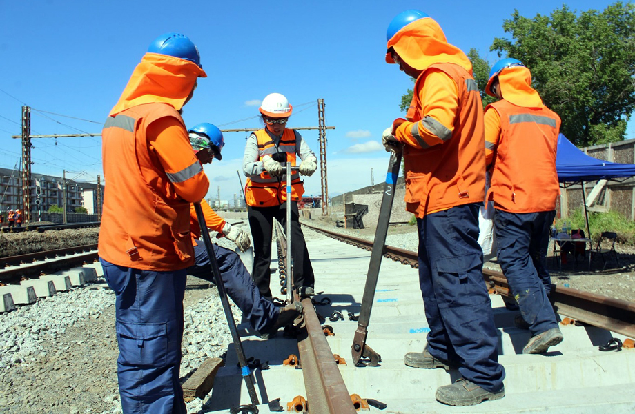 Equipo de trabajadores ferroviarios alineando y fijando un riel sobre durmientes de concreto