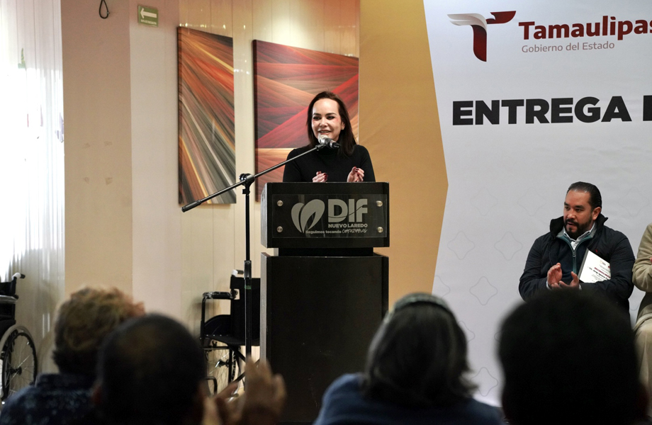 Funcionaria del Gobierno Municipal ofrece un mensaje en el podio del DIF Nuevo Laredo ante personas en sillas de ruedas y asistentes al acto de apoyo a personas con discapacidad