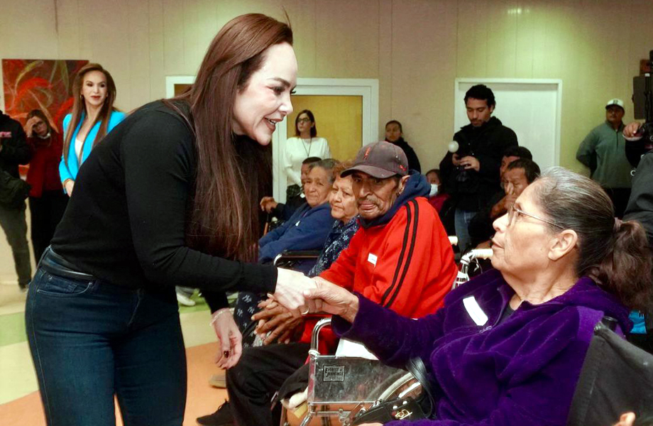 Carmen Lilia Canturosas saluda de mano a una mujer adulta mayor en silla de ruedas durante la jornada de entrega de sillas de ruedas y andadores