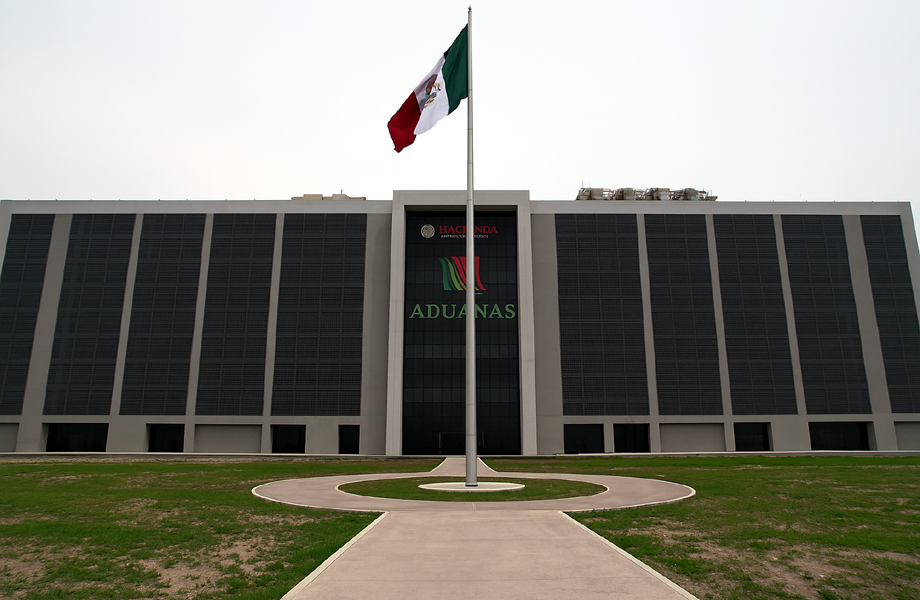 Edificio frontal de la Agencia Nacional de Aduanas de Mxico en Nuevo Laredo con una gran bandera de Mxico en el patio central