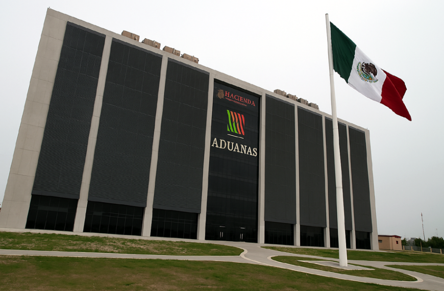 Edificio moderno de la ANAM en Nuevo Laredo visto en ángulo, con la bandera de México ondeando en primer plano