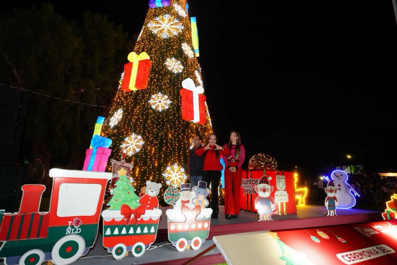 Alcaldesa de Nuevo Laredo y su familia frente al pino navideo gigante iluminado y un tren decorativo en el Parque Viveros
