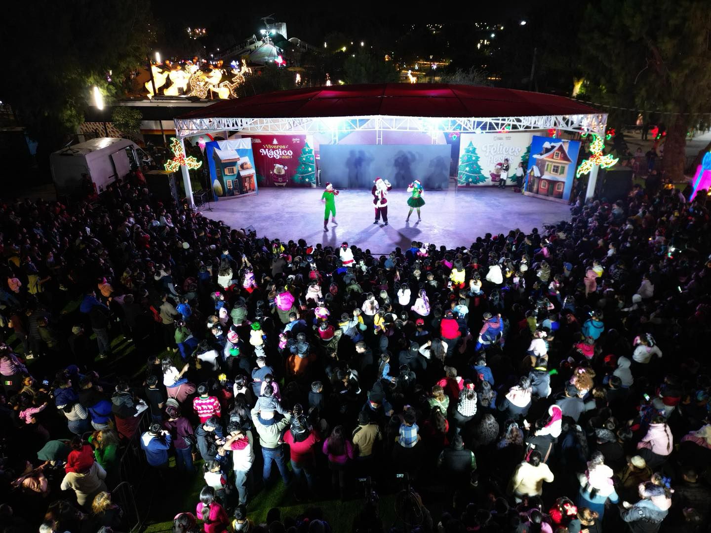Vista desde arriba de un escenario navideo con Santa Claus y artistas frente a una gran multitud en el Parque Viveros