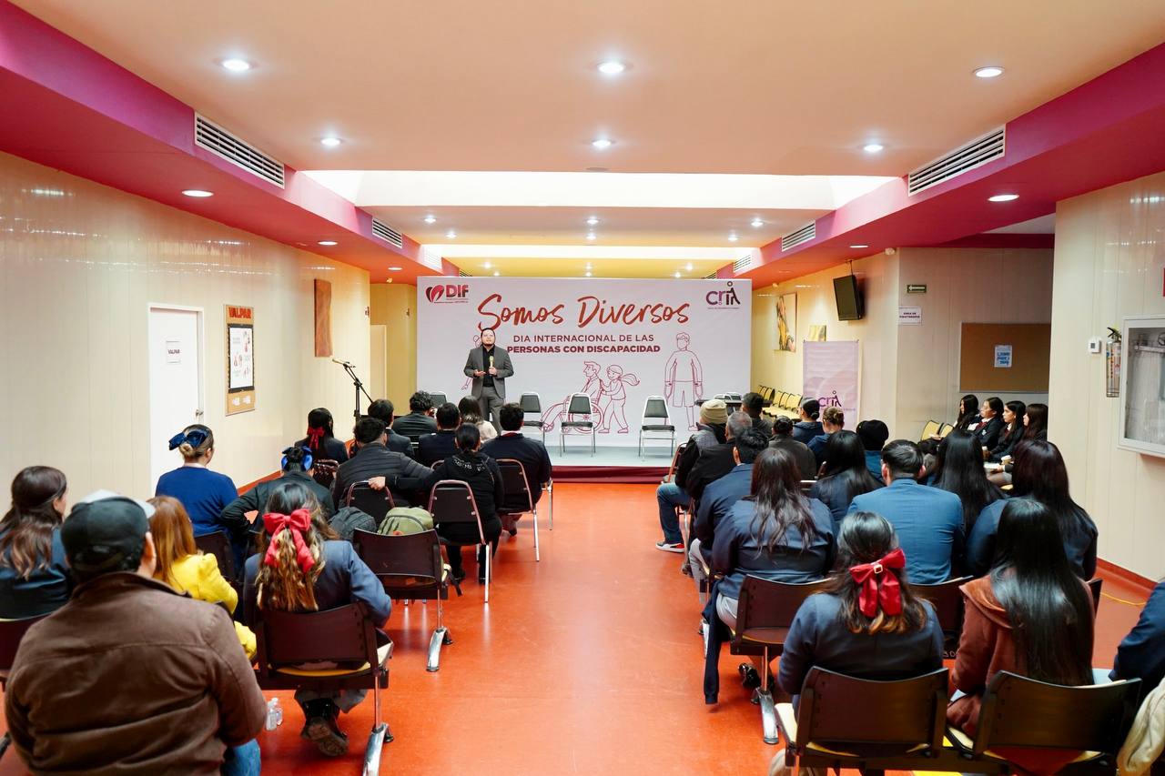 Ponente de pie en el escenario del Foro Somos Diversos con la lona del Da Internacional de las Personas con Discapacidad