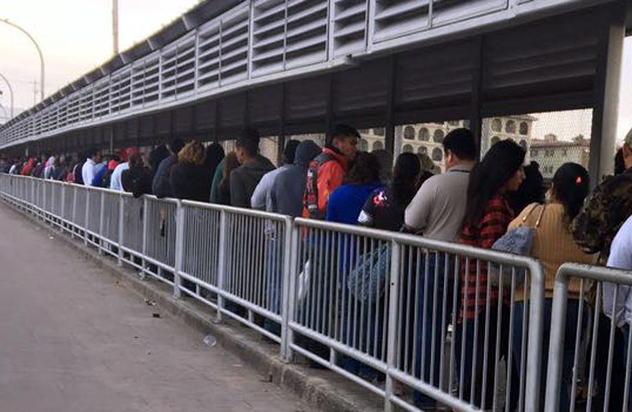 Larga fila de personas avanza lentamente por el puente peatonal internacional en espera de cruzar hacia Estados Unidos