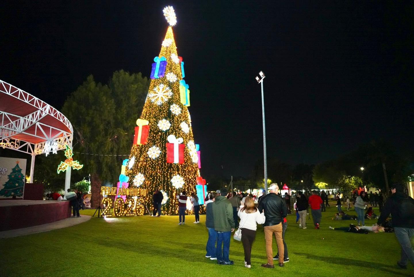 Familias caminando frente a un rbol navideo gigante iluminado en el Viveros Mgico de Nuevo Laredo