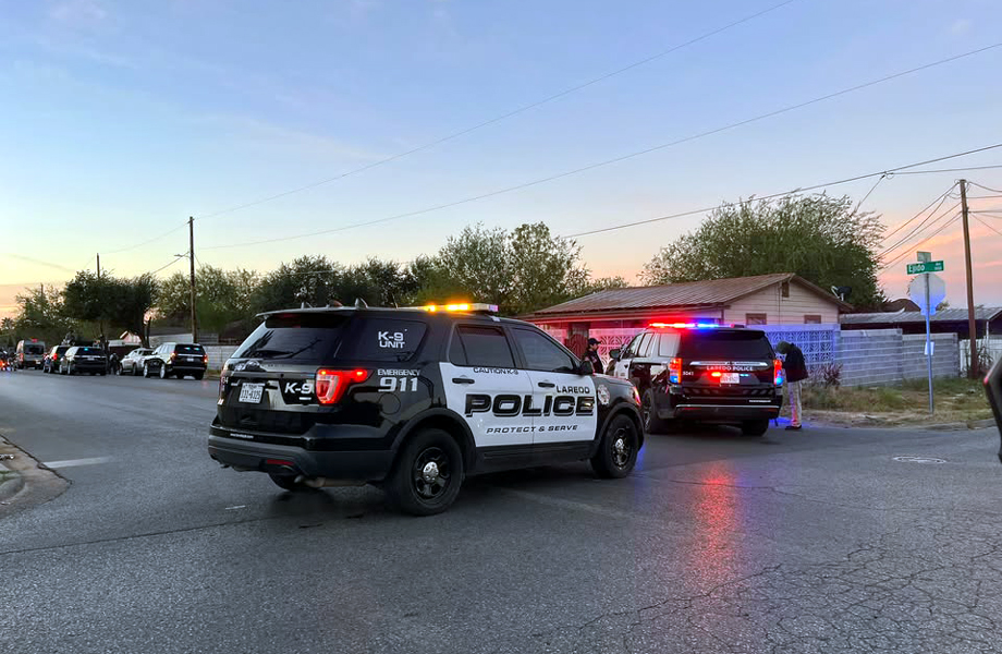 Patrullas del Departamento de Policía de Laredo bloquean una calle residencial durante un operativo de cateo al atardecer.