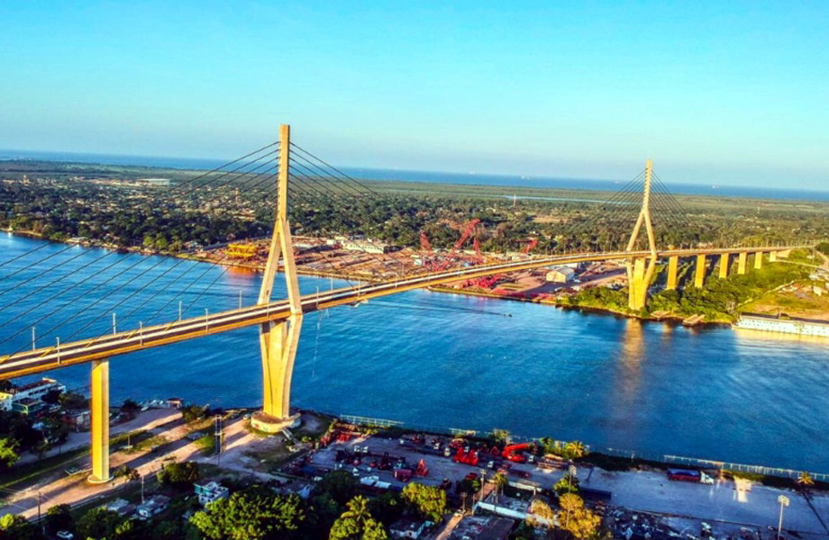 Puente atirantado cruzando un ro amplio con costa y zona urbana al fondo
