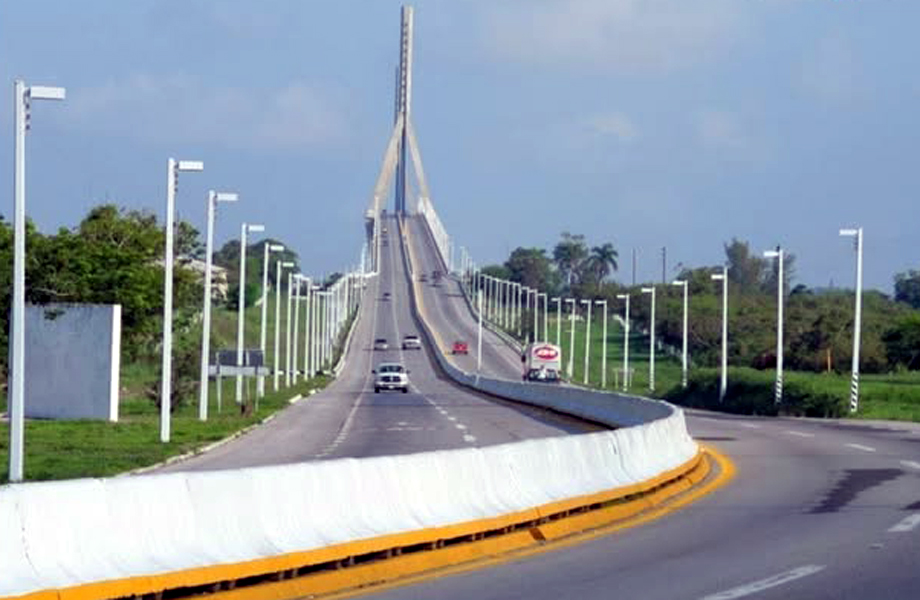 Carretera de varios carriles que sube hacia un puente atirantado con luminarias en ambos lados