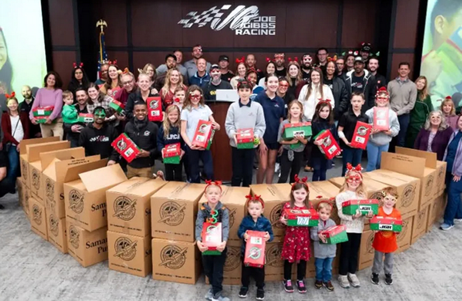 Grupo de voluntarios y nios posando con cajitas navideas de Samaritans Purse frente a decenas de cajas de embarque