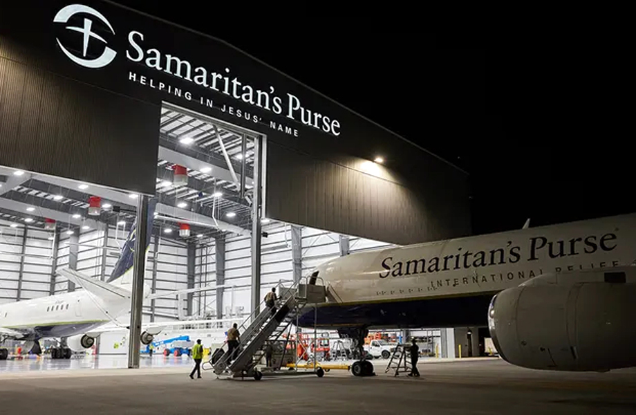 Avin de ayuda humanitaria dentro de un hangar iluminado con el letrero Samaritans Purse de noche