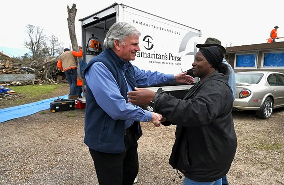 Colaborador de Samaritans Purse abrazando a una mujer frente a una camioneta de ayuda en rea con daos