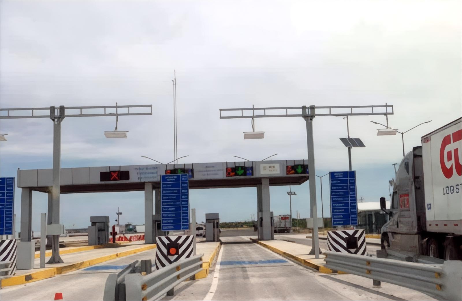 Vista general de plaza de cobro con varios carriles y camiones de carga en autopista de cuota del noreste