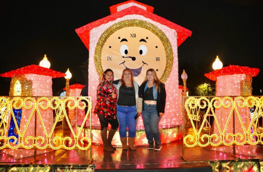 Tres mujeres posan frente a un reloj monumental iluminado como parte del recorrido navideño en El Viveros Mágico.