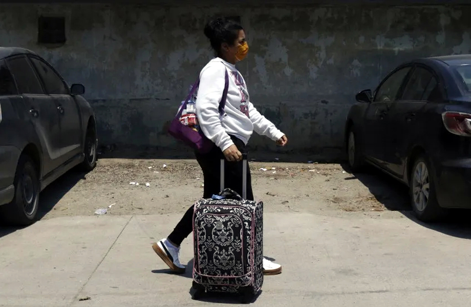 Persona migrante camina con una maleta durante un proceso de salida voluntaria de Estados Unidos.