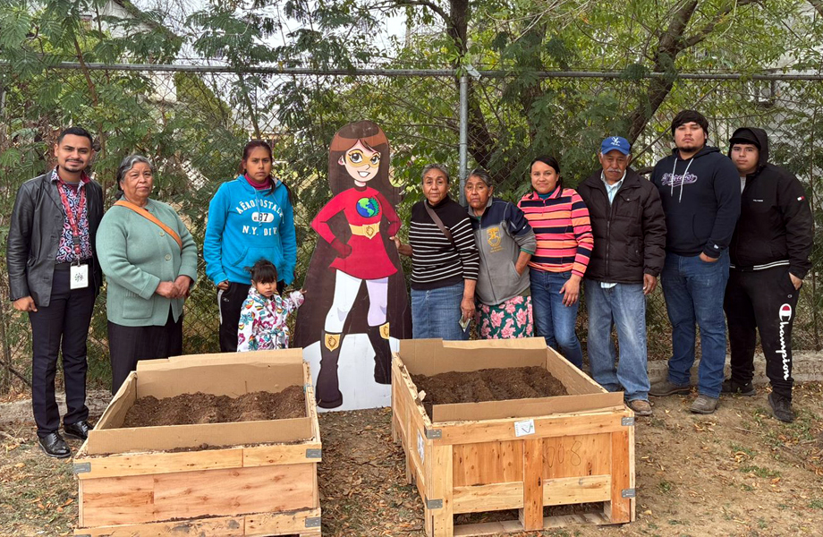 Vecinas y vecinos posan junto a cajones de cultivo instalados para el huerto urbano en un espacio comunitario de Nuevo Laredo.