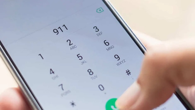 Close-up of a smartphone dialer screen with numbers 1–9 and a green call button, a finger about to press the 0 key.