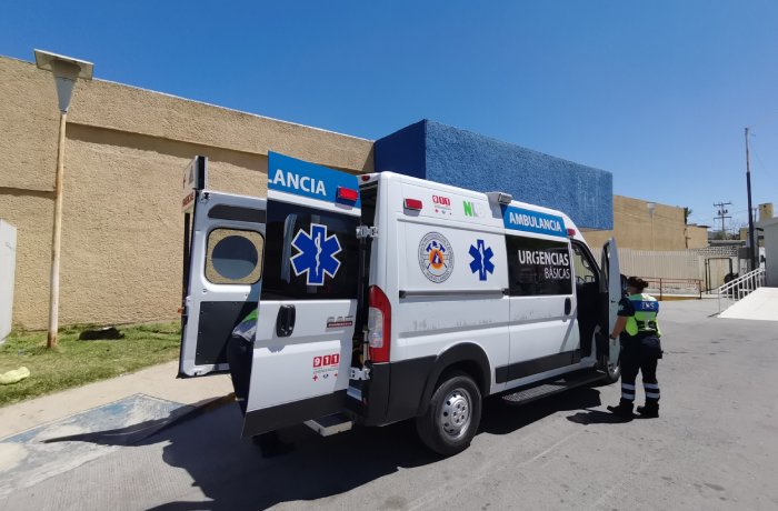 Two ambulances parked outside a building; a paramedic in reflective gear stands by the rear door.
