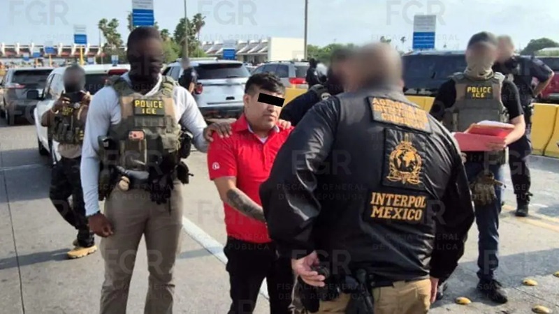 Law enforcement officers in tactical vests surround a man in a red shirt on a highway, his face blurred for privacy, with several officers nearby.