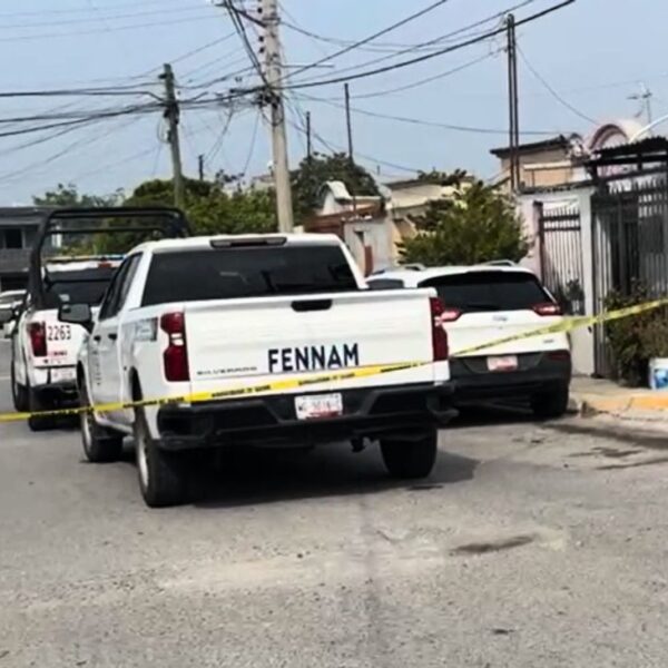 Yellow police tape blocks a residential street, with a white pickup and other parked cars in view after an incident.