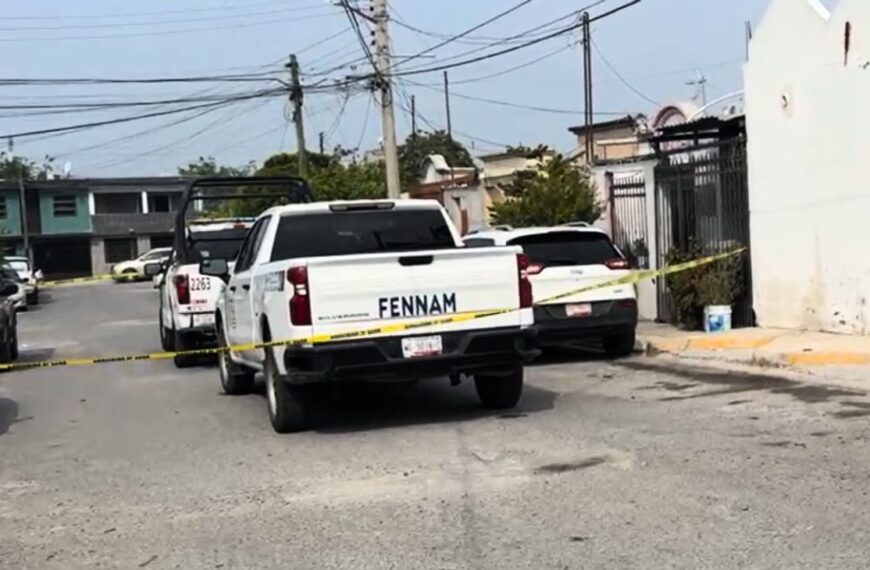 Yellow police tape blocks a residential street, with a white pickup and other parked cars in view after an incident.