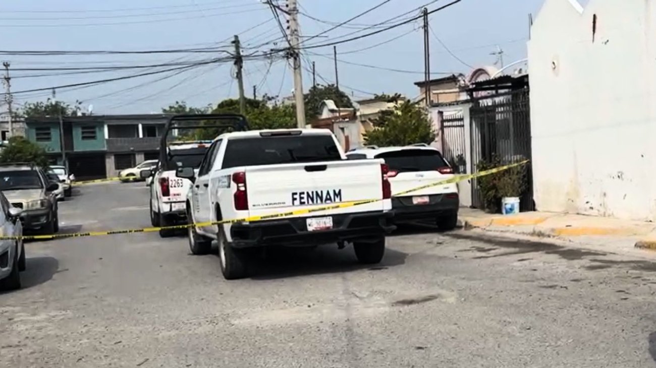 Yellow police tape blocks a residential street, with a white pickup and other parked cars in view after an incident.