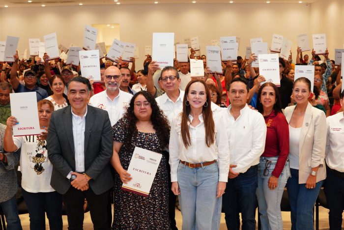 Group of people in a hall posing for a photo, many holding up certificates; front row features men and women in business casual attire.