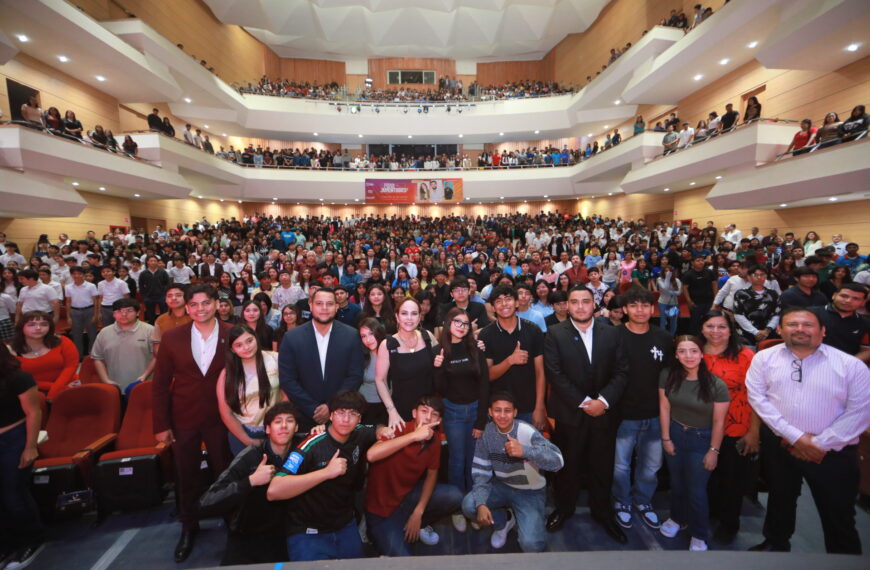 Group photo of hundreds of students and attendees gathered in a multi-level auditorium, posing for a front-row shot.