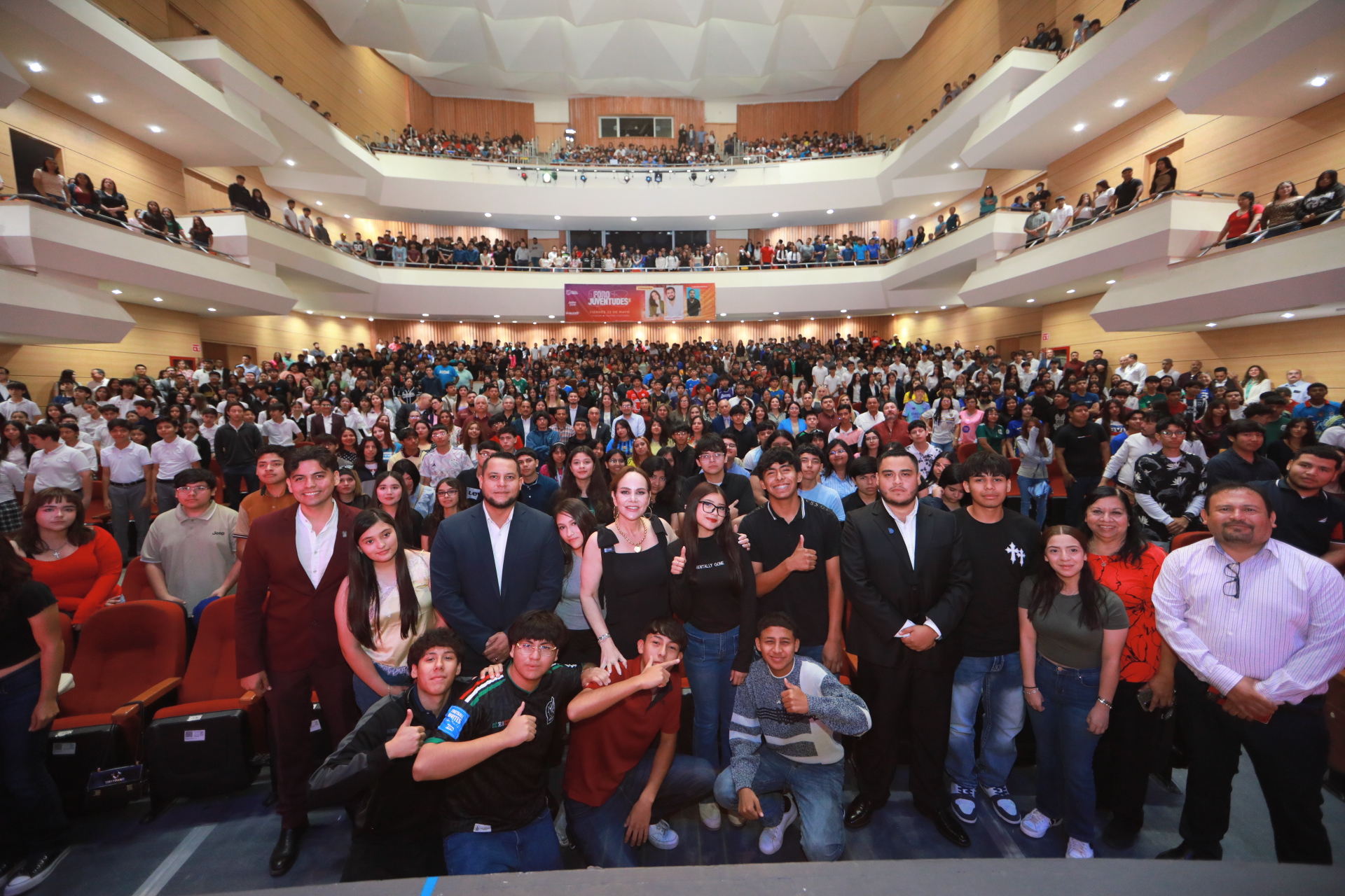 Group photo of hundreds of students and attendees gathered in a multi-level auditorium, posing for a front-row shot.