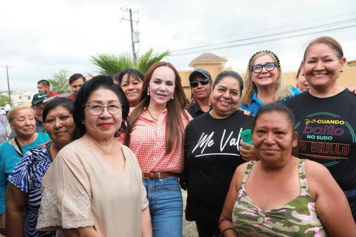 Group of diverse women posing together outdoors at a community event, smiling for the camera on a sunny day.