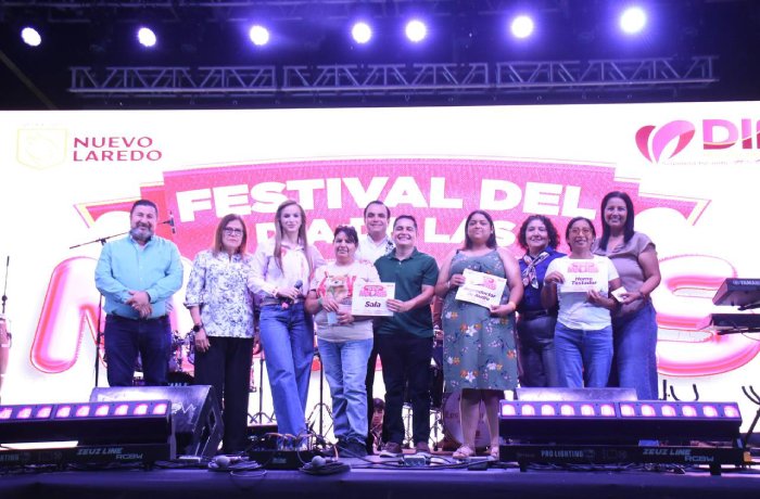 Group of ten people on a festival stage, some holding certificates, in front of a bright banner that reads FESTIVAL DEL.