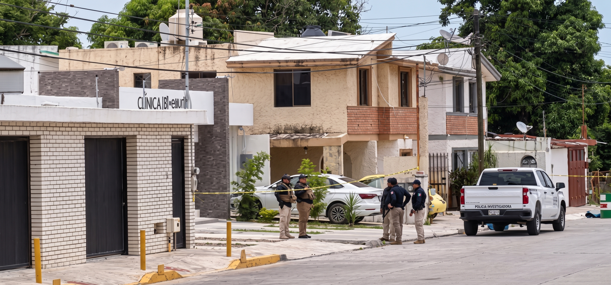 Group of police officers standing on a residential street near a crime scene with yellow tape and a white investigation pickup in the background.