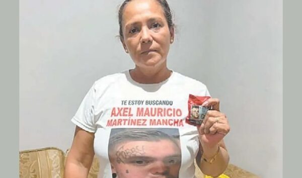 Woman in a white T-shirt with a missing-person poster on the front, holding a small red flyer.