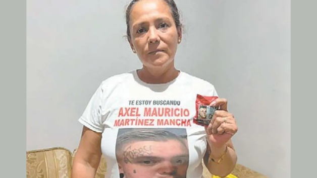 Woman in a white T-shirt with a missing-person poster on the front, holding a small red flyer.