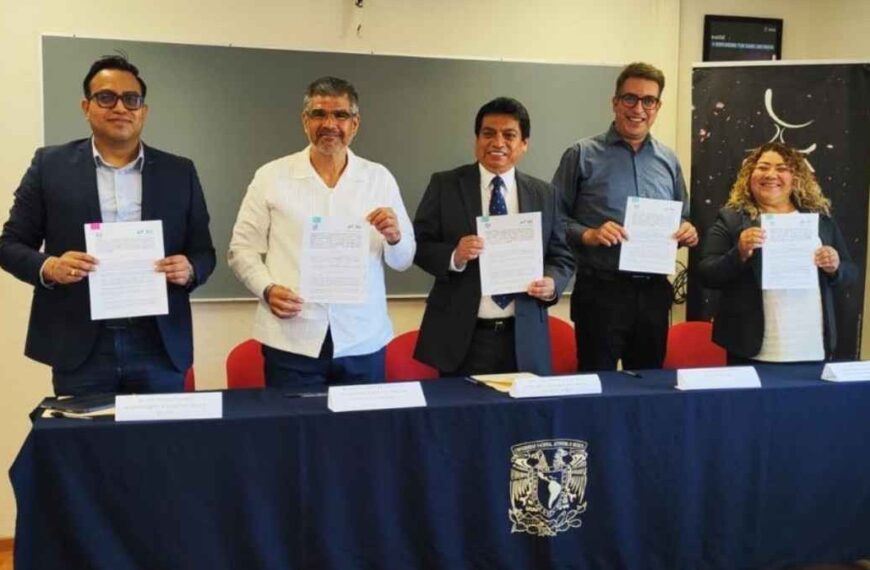 Five professionals in business attire stand behind a table, each holding signed documents during a formal signing ceremony.